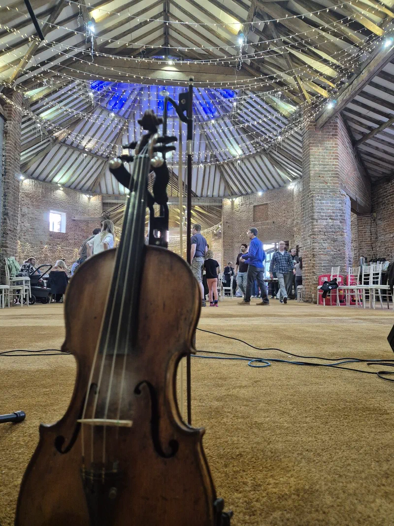 A fiddle resting in a barn with guests behind