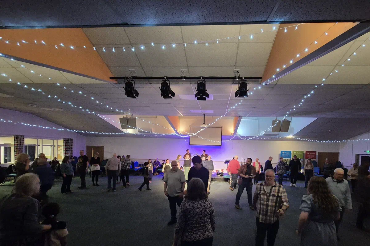 A wide view of a hall with fairy lights and dancers gathering