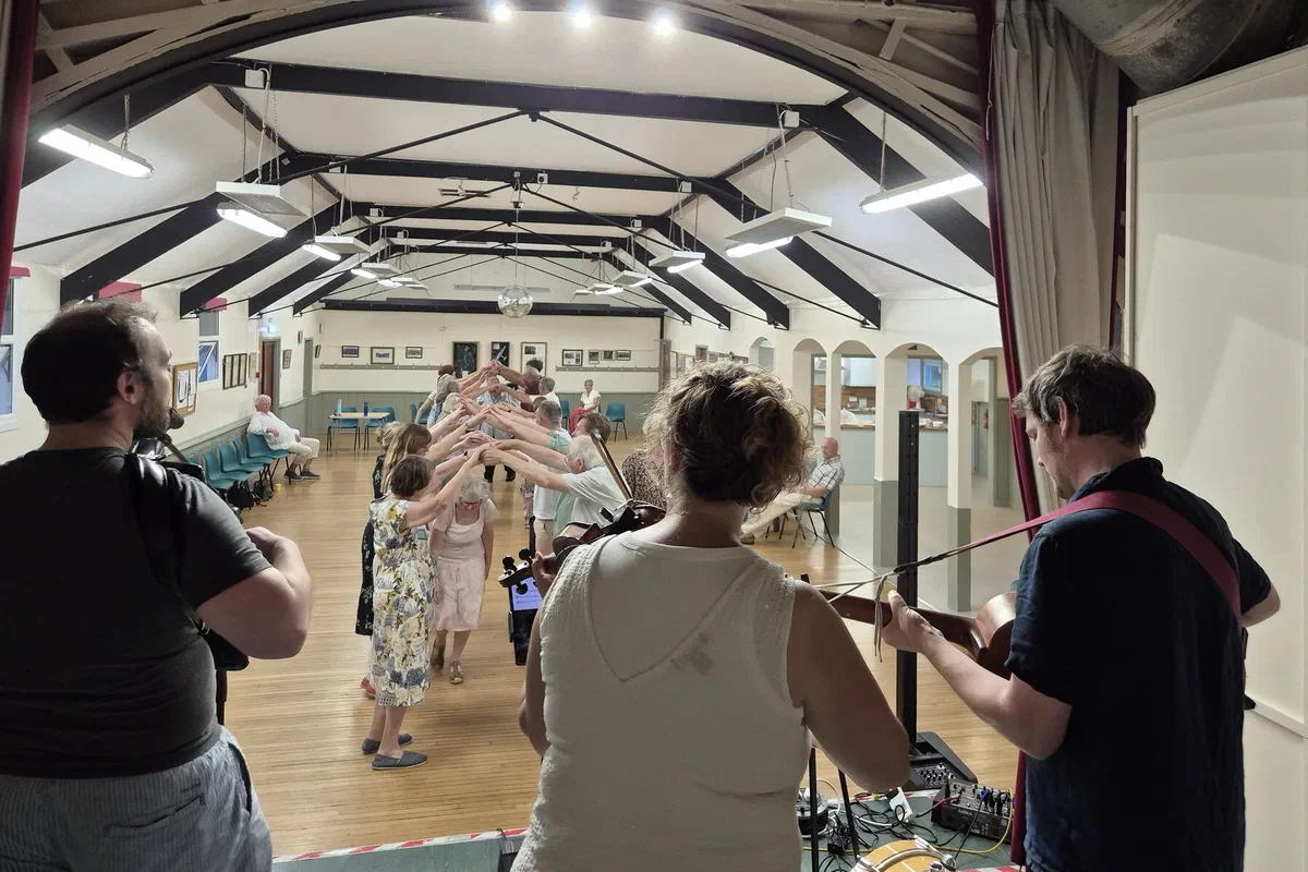 A hall full of dancers forming an arch while the band plays